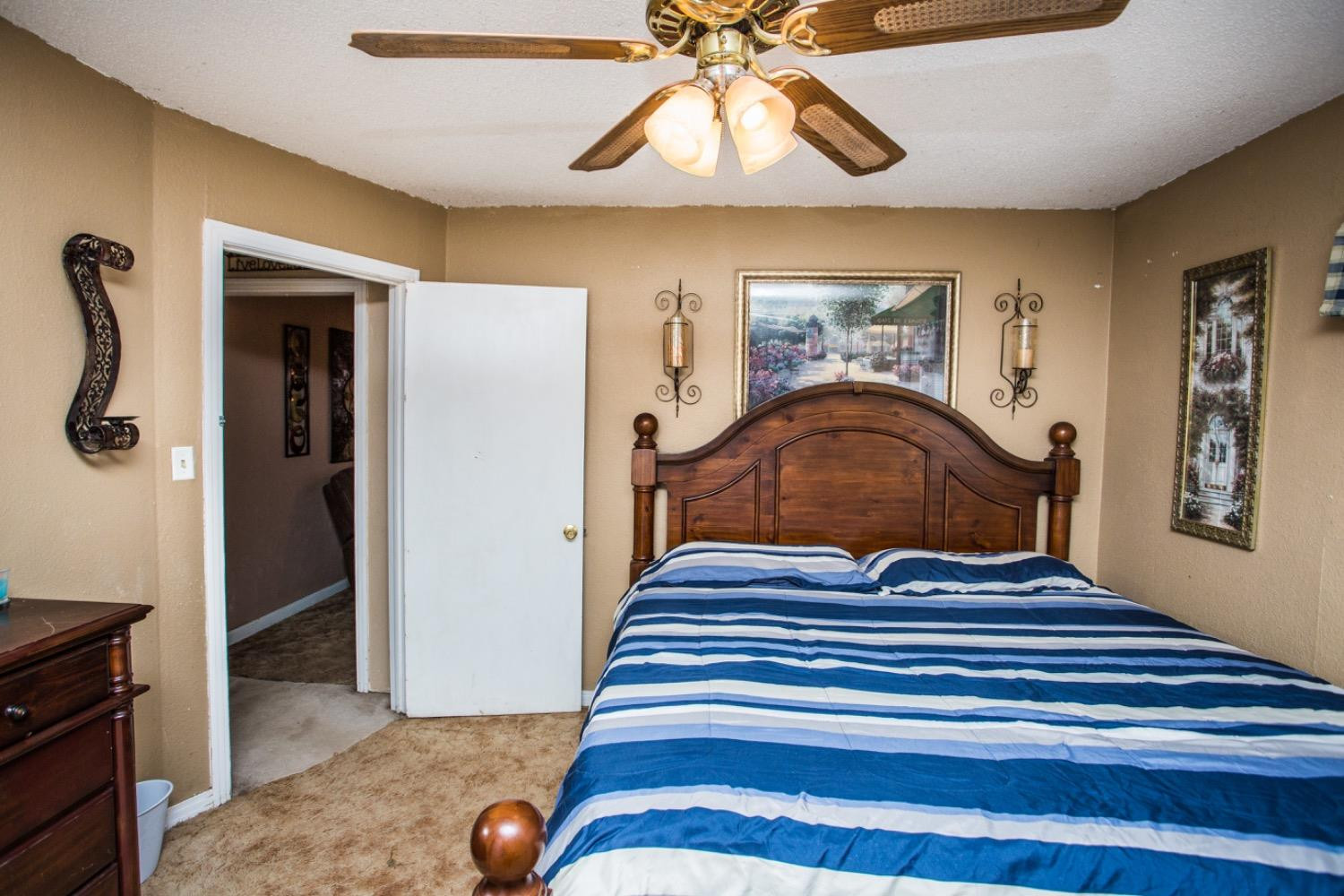 306 Terry Avenue Wellman, TX 79316 - Photo 14 of 32 a bedroom with a bed and a chandelier