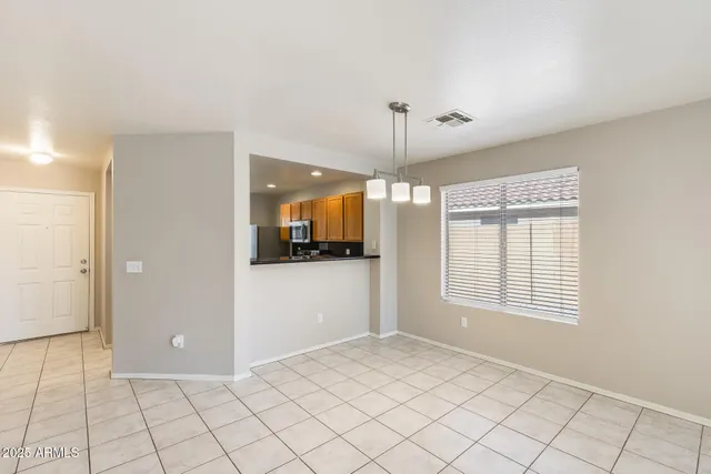 a view of an empty room with window and chandelier fan