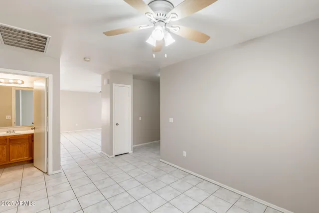 an empty room with chandelier fan and windows