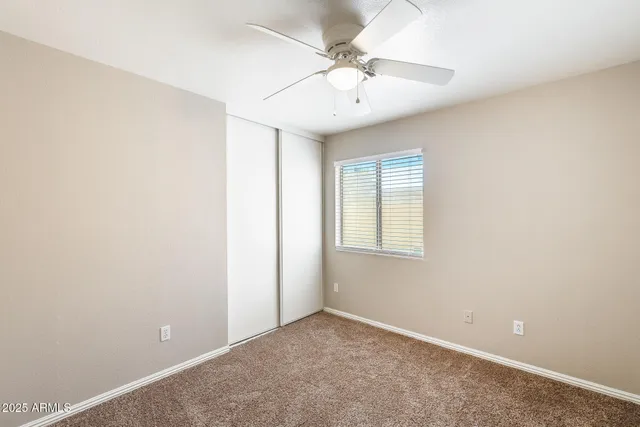 an empty room with a chandelier fan and closet area
