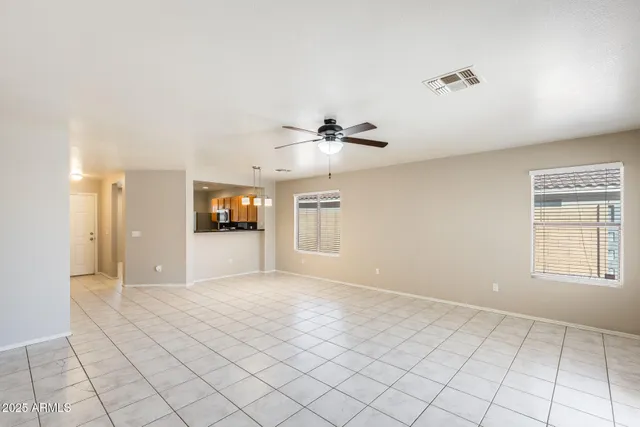a view of an empty room with window and chandelier fan