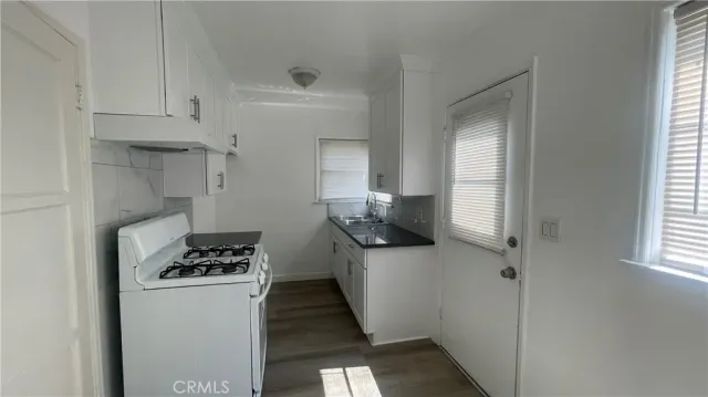 a kitchen with stainless steel appliances a refrigerator a sink and white cabinets