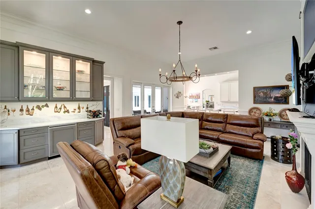a living room with furniture a chandelier and a kitchen view