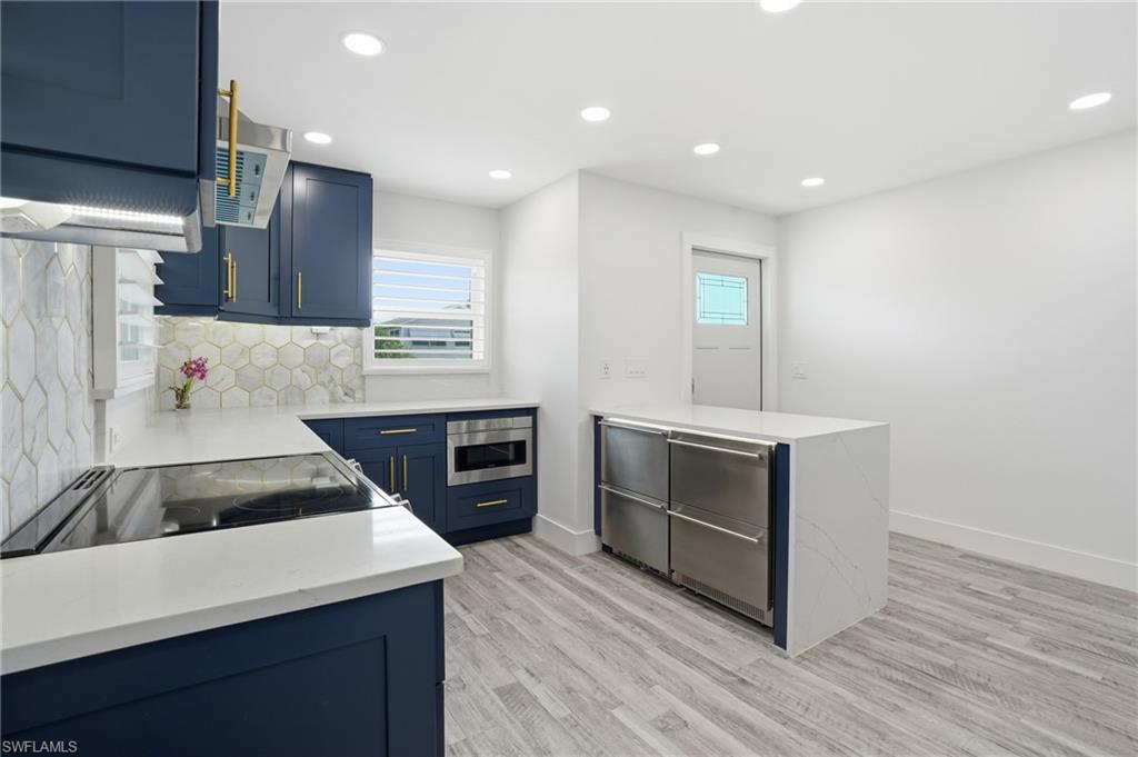 270 Dundee Road Fort Myers Beach, FL 33931 - Photo 17 of 48 Kitchen with a peninsula, light stone countertops, blue cabinets, recessed lighting, and tasteful backsplash - Virtually Edited Image
