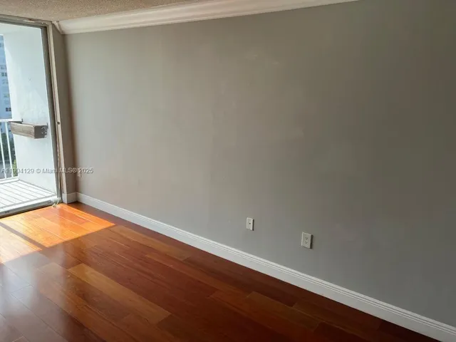 an empty room with wooden floor and a window