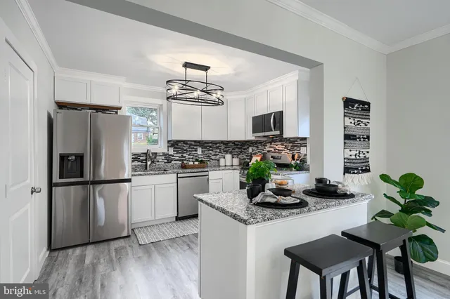 a kitchen with stainless steel appliances a refrigerator a sink a stove white cabinets and wooden floor