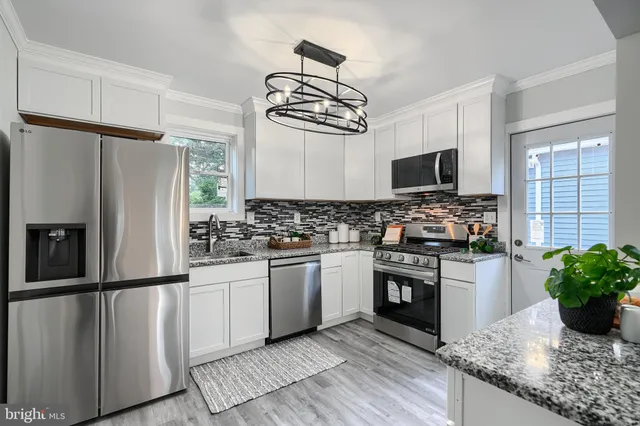 a kitchen with granite countertop a refrigerator stove and sink