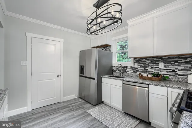 a kitchen with stainless steel appliances a refrigerator a sink and white cabinets