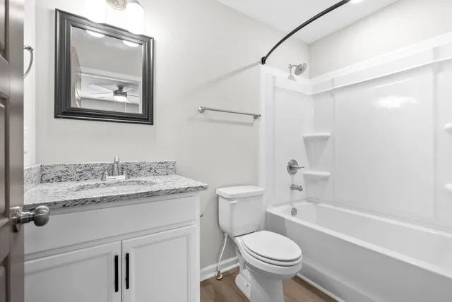a bathroom with a granite countertop toilet a sink and a bathtub