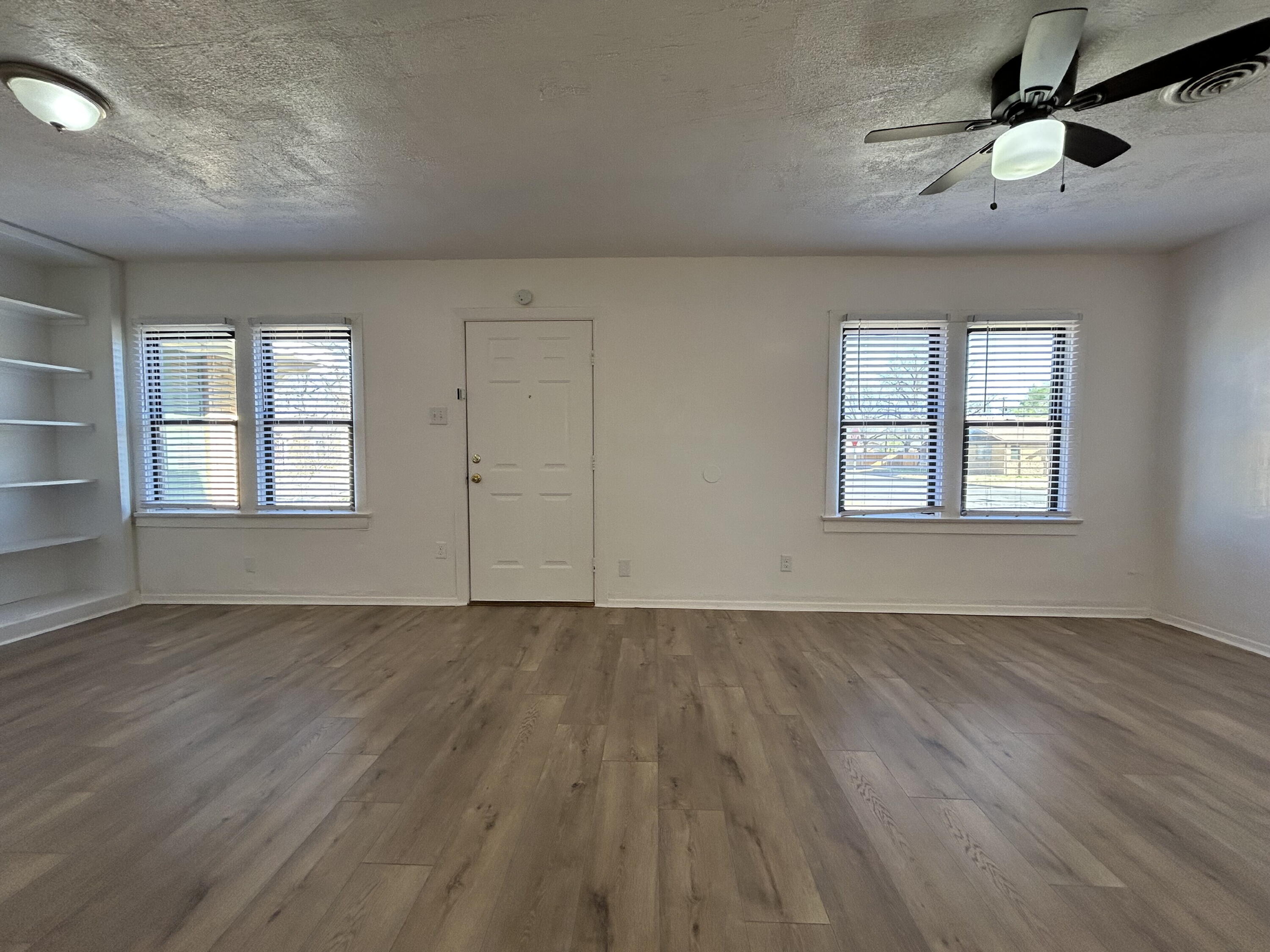2201 28th Street, Unit FRONT Lubbock, TX 79411 - Photo 3 of 23 an empty room with wooden floor chandelier fan and windows