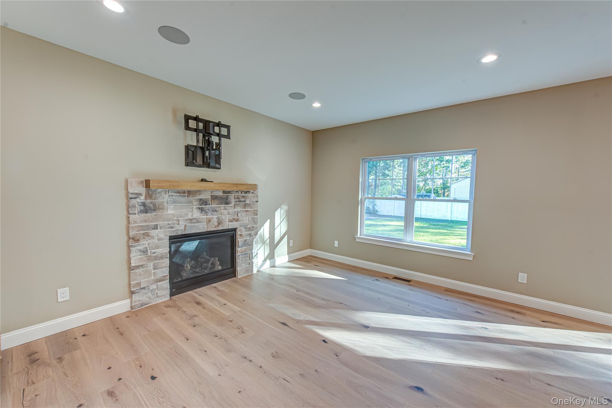 64 Blydenburgh Road Centereach, NY 11720 - Photo 13 of 44 Unfurnished living room featuring a fireplace, light wood-style flooring, and recessed lighting. For Marketing Purposes!