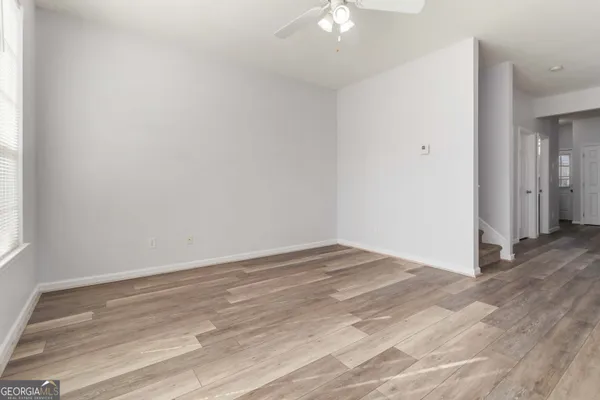 a view of an empty room with wooden floor and a window