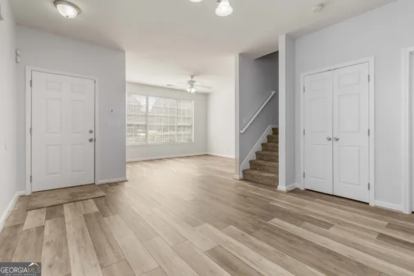 an empty room with wooden floor staircase and windows