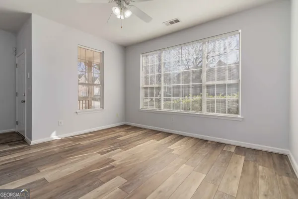 a view of an empty room with a window and wooden floor