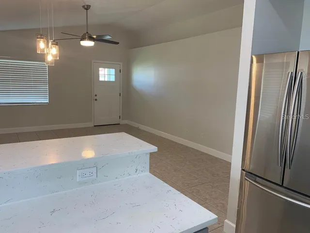 a view of an empty room with window and a chandelier fan