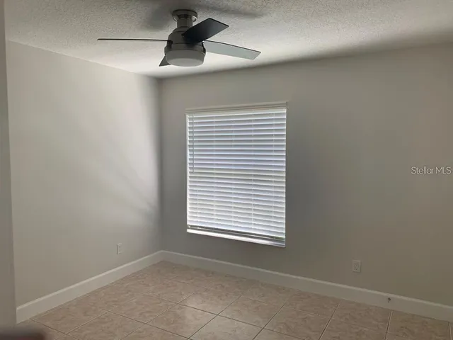an empty room with a window and ceiling fan