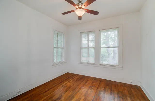 an empty room with wooden floor closet and windows