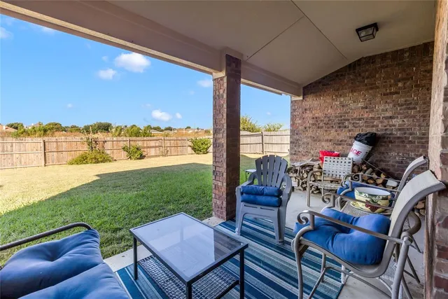 a view of a patio with lawn chairs floor to ceiling window plants and ocean view