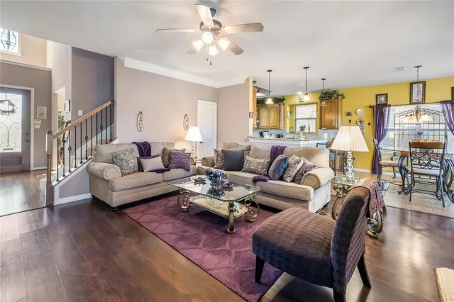 a living room with furniture kitchen view and a wooden floor