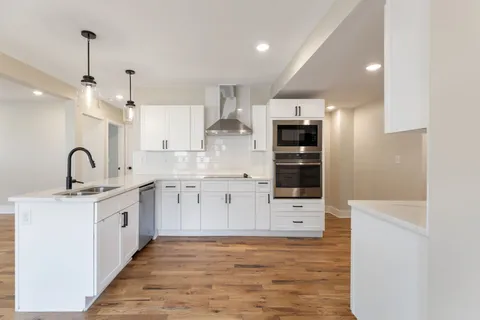 a large kitchen with stainless steel appliances a large counter top a stove and a refrigerator