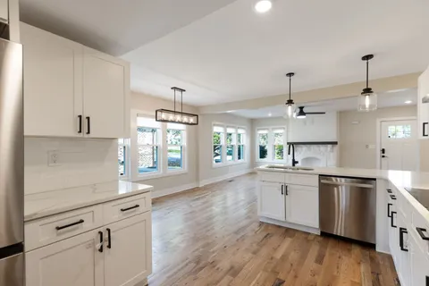 a kitchen with granite countertop white cabinets and white appliances