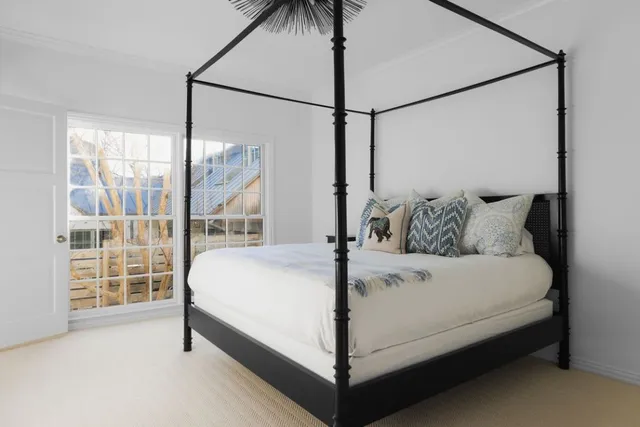 a white bed sitting in a bedroom next to a window