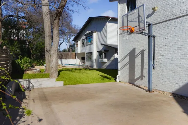 a view of yellow house with a small yard and a large tree