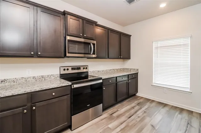 a kitchen with stainless steel appliances granite countertop a stove a sink and a microwave