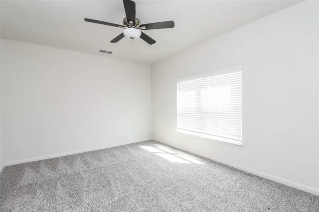an empty room with a window and a fan