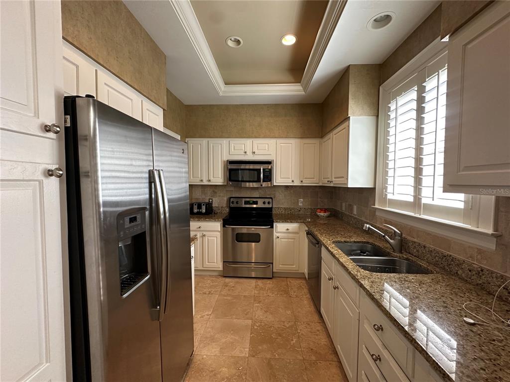 60 Bishopscourt Road, Unit 114 Osprey, FL 34229 - Photo 4 of 33 a kitchen with stainless steel appliances granite countertop a refrigerator a sink a stove a microwave and wooden cabinets