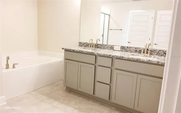 a bathroom with a granite countertop sink and a bathtub