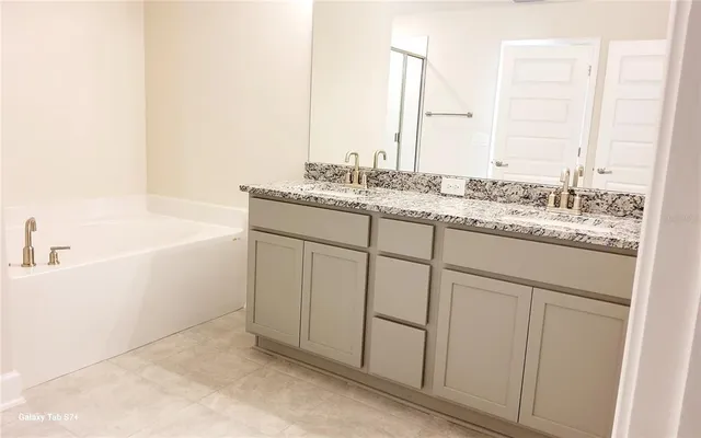a bathroom with a granite countertop sink and a bathtub