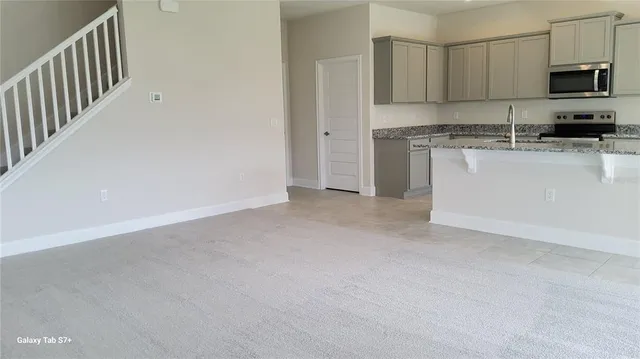 a view of a kitchen with stainless steel appliances granite countertop a stove a sink and a microwave