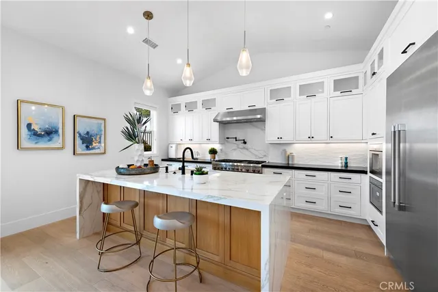 a kitchen with stainless steel appliances kitchen island granite countertop a table chairs sink and cabinets