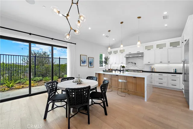 a kitchen with stainless steel appliances kitchen island granite countertop a dining table chairs and white cabinets