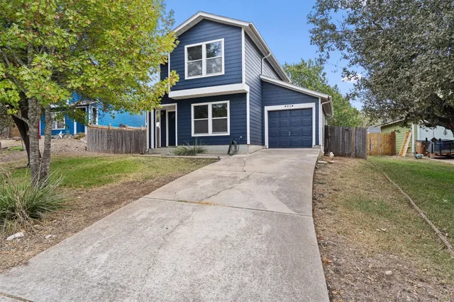 a front view of a house with a yard and trees