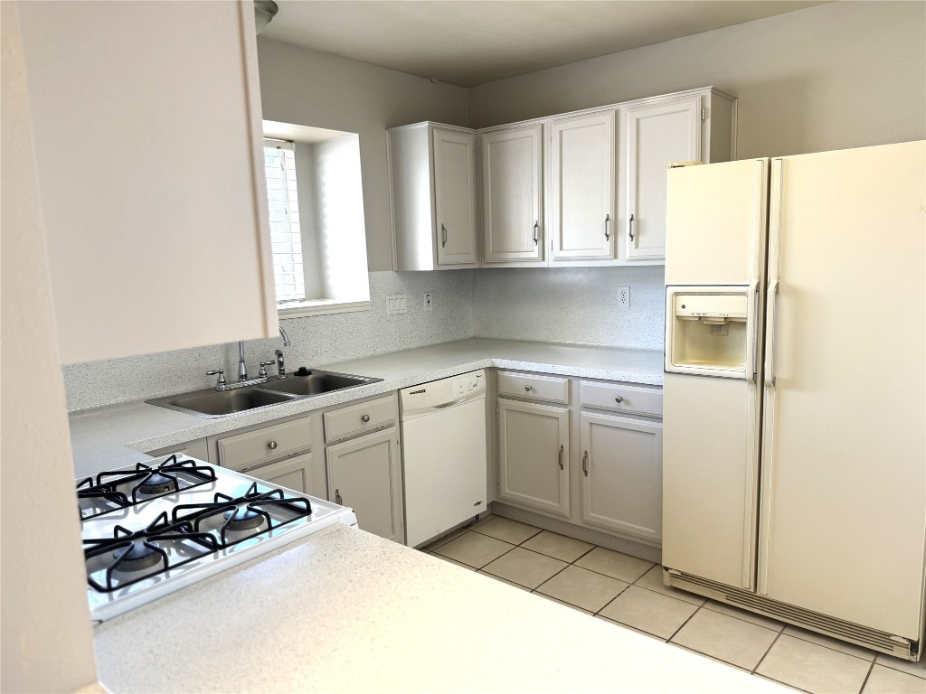 1412 Quail Run Road Pflugerville, TX 78660 - Photo 7 of 16 a kitchen with a refrigerator and white cabinets