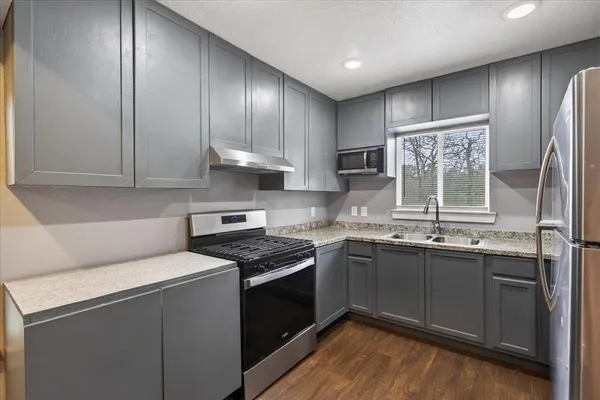 a kitchen with stainless steel appliances granite countertop a sink stove and refrigerator