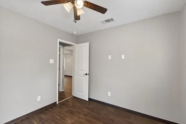 an empty room with wooden floor and ceiling fan