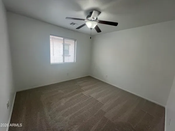 an empty room with a ceiling fan and window