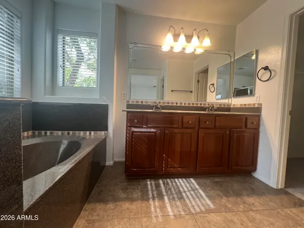 a spacious bathroom with a tub sink and mirror