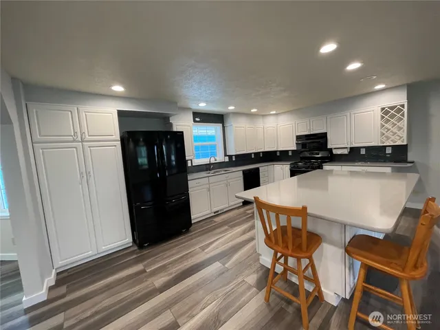 a kitchen with stainless steel appliances a refrigerator a sink dishwasher and a microwave with wooden floor