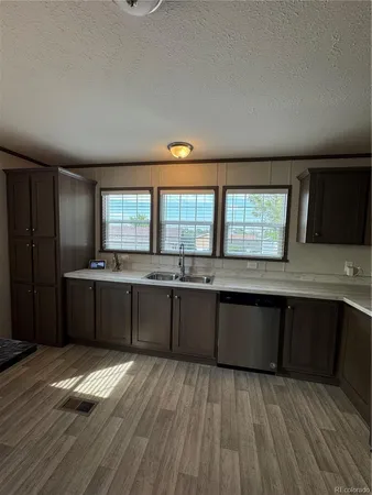 a kitchen with granite countertop a stove a sink wooden floor and cabinets