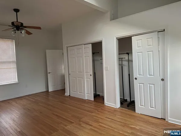 an empty room with wooden floor closet and windows