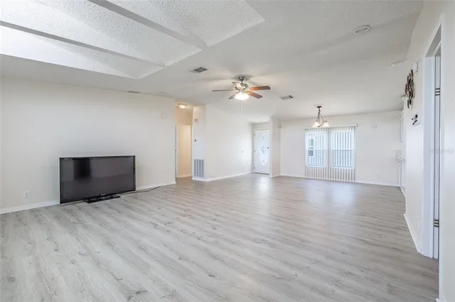 a view of an empty room with window and wooden floor