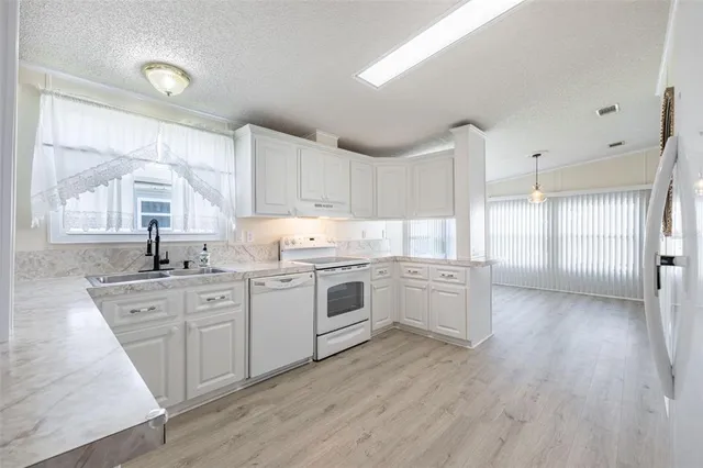 a kitchen with granite countertop white cabinets and white appliances