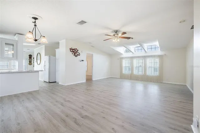 an empty room with wooden floor fan and windows