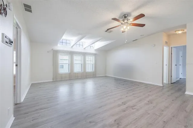 a view of an empty room with a window and wooden floor