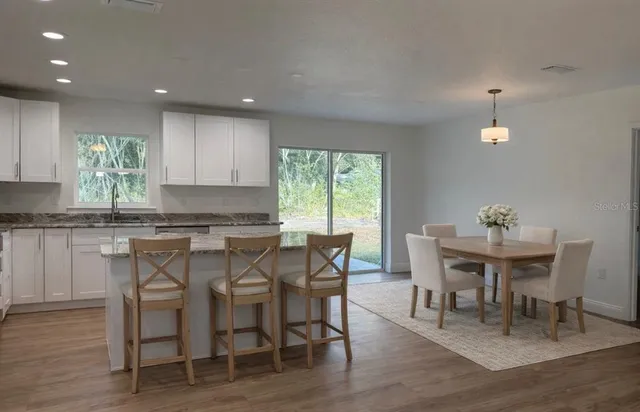 a kitchen with a dining table chairs and wooden floor