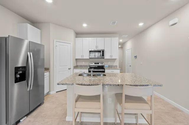 a kitchen with granite countertop a refrigerator and a stove top oven
